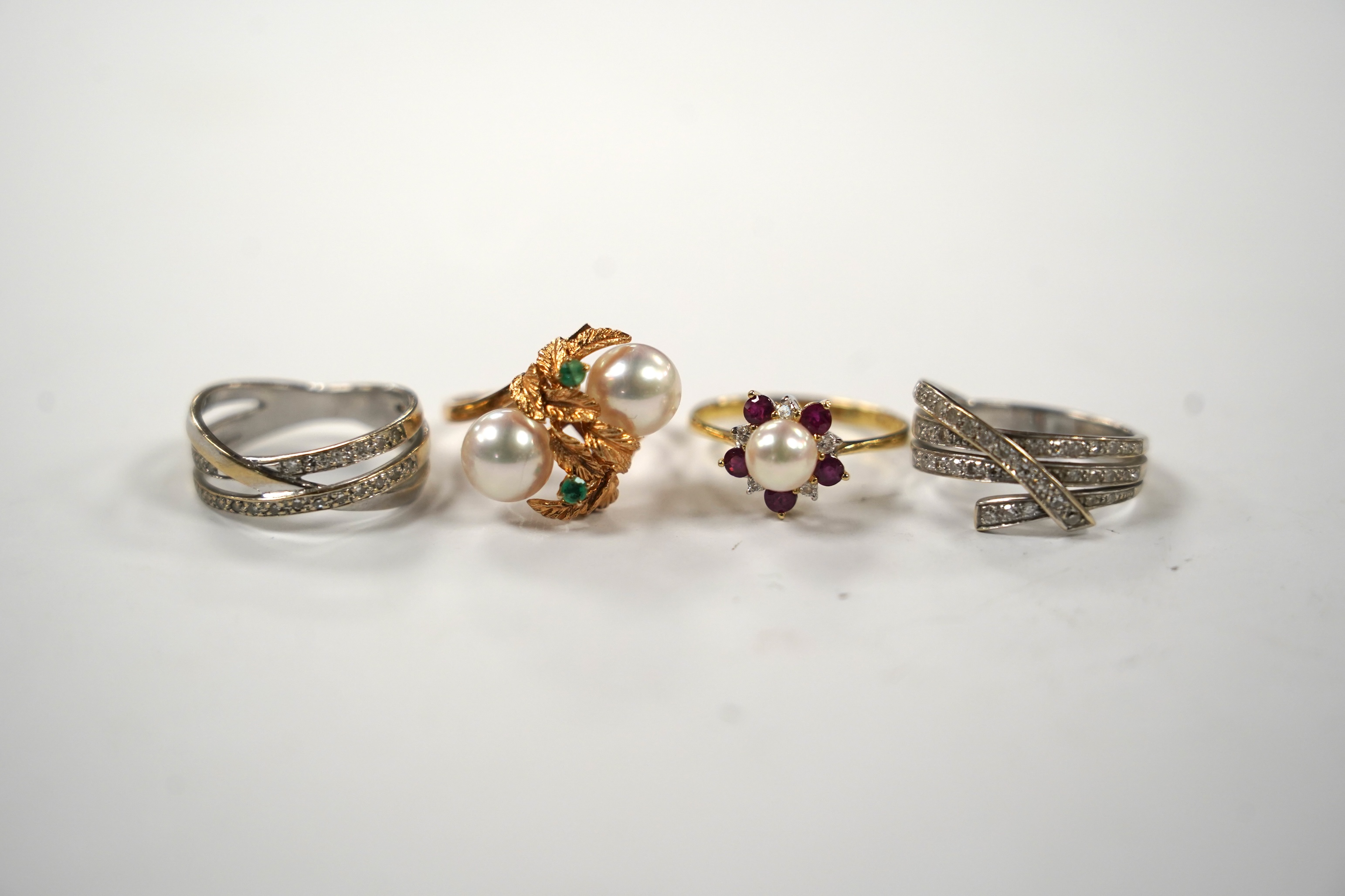 Two modern continental yellow metal and diamond chip set triple band cross over rings, size N, a 14k, ruby, diamond and cultured pearl set cluster ring, a 14k, two stone cultured pearl and a two stone emerald set ring.